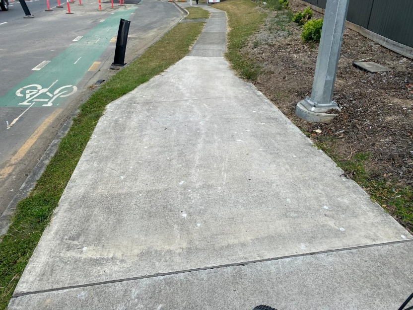 A sidewalk with grass and a sign AI-generated content may be incorrect.